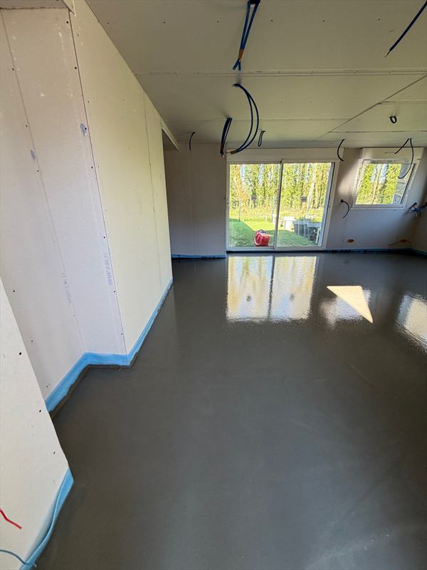 Chape liquide coulée vue depuis l'angle de la pièce, bande périphérique bleue le long des cloisons