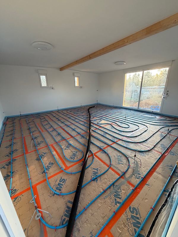 Boucles de plancher chauffant agrafées sur panneaux isolants, sous une poutre bois apparente